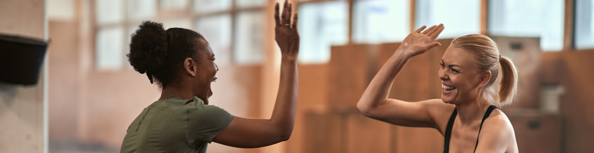 Two women sitting on gym floor exchanging a high five