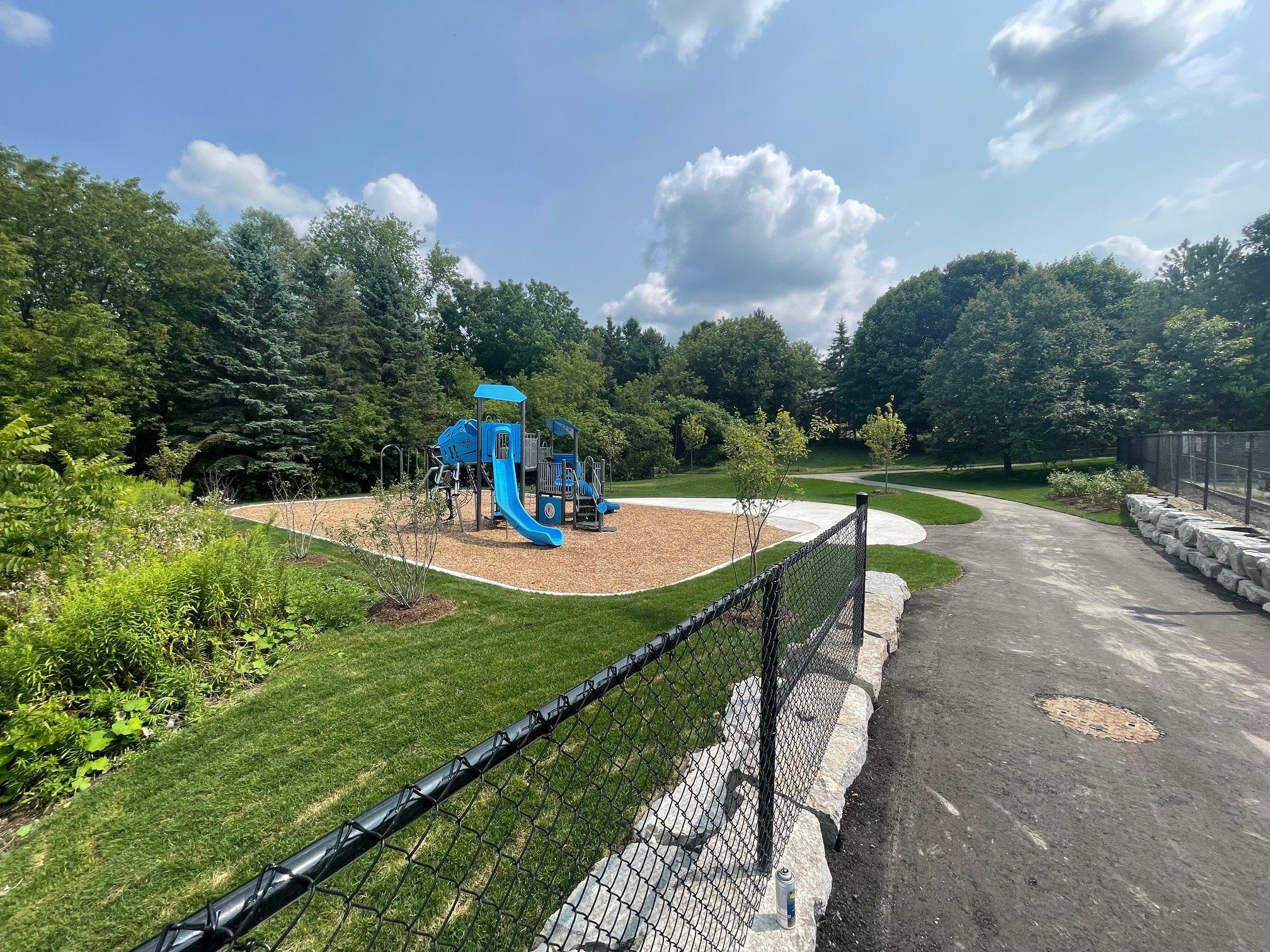 Picture of Emily Park redeveloped, with trees in the background and newly paved walkway